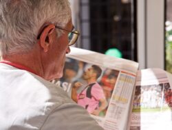 Old man with glass reading news