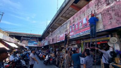 Petugas Bapenda Padang saat mencopoti reklame Ilegal dari sebuah toko.