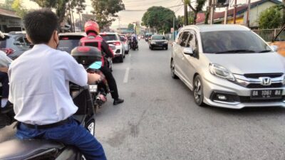 Seorang pelajar SMP di Kota Padang tanpa helm terjebak lampu merah di perempatan lampu merah Alai, Kota Padang saat menuju sekolah