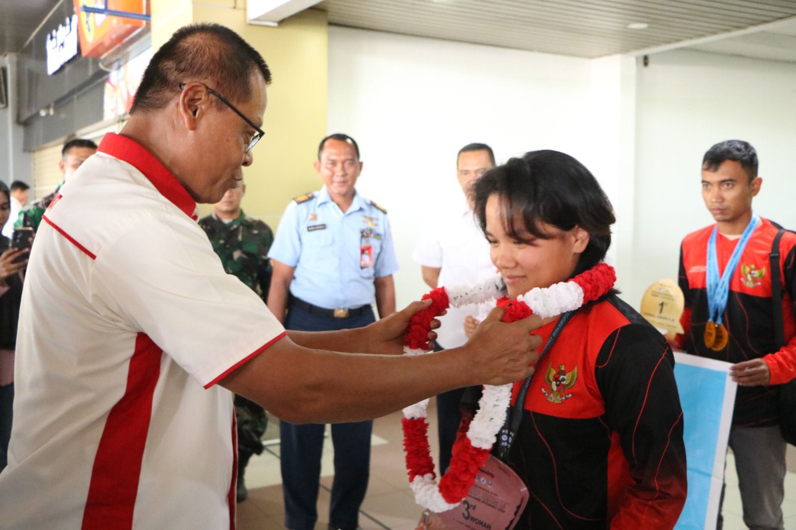 Sekretaris Umum KONI Sumbar Prof Alnedral memasangkan kalungan bunga kepada salah seorang atlet saat mendarat di BIM.